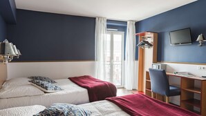 A hotel room with two beds, a desk, a chair, a TV, and a window with a view of the outside. - Brit Hotel De Paris (Saint-Jean-de-Luz)