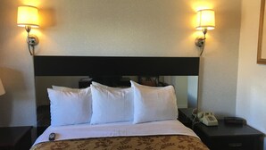 A hotel room with a bed, two bedside lamps, a telephone, and a nightstand. - Pacific Heights Inn (San Francisco)