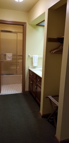 A bathroom with a glass shower door, a sink with a mirror, and a towel rack.