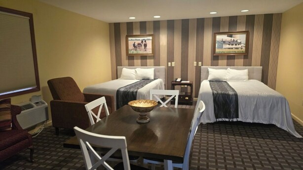 Habitación de hotel con dos camas, una mesa de comedor y una silla.