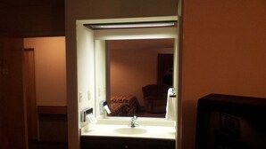 Un baño de hotel con lavabo, espejo y dispensador de toallas.