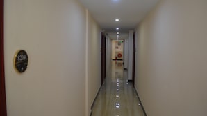 A hotel hallway with a polished floor, a sign on the wall, and a door at the end. - Good Luck Hotel (Yangon)