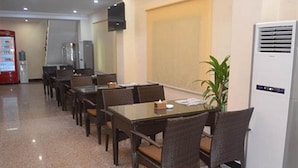 A conference room with a long table, chairs, a plant, and a white air conditioning unit. - Good Luck Hotel (Yangon)
