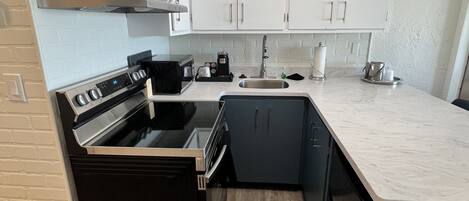 Una cocina moderna con armarios blancos, una estufa negra y un lavamanos de acero inoxidable.