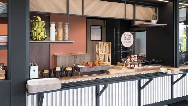 A breakfast bar with bread, pastries, and condiments. - B&B HOTEL Laval Ouest (Laval)