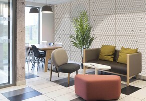 Un área de espera moderna con un sofá, sillas, una mesa de comedor y una planta en maceta.