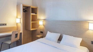 A hotel room with a bed, a desk with a chair, a wardrobe, and two wall-mounted lamps. - B&B HOTEL Laval Ouest (Laval)