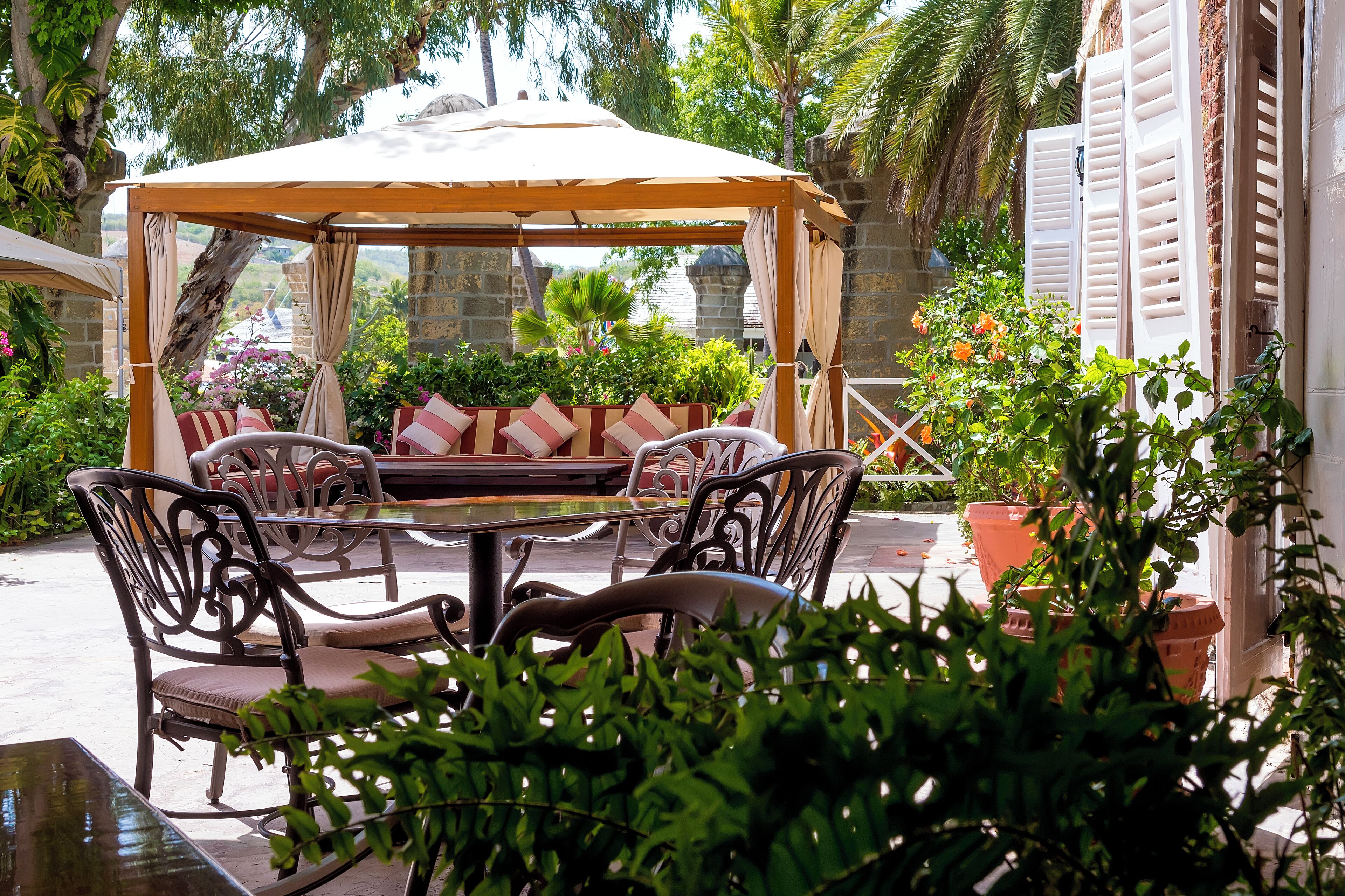 An outdoor patio with a covered seating area, a table, and chairs.