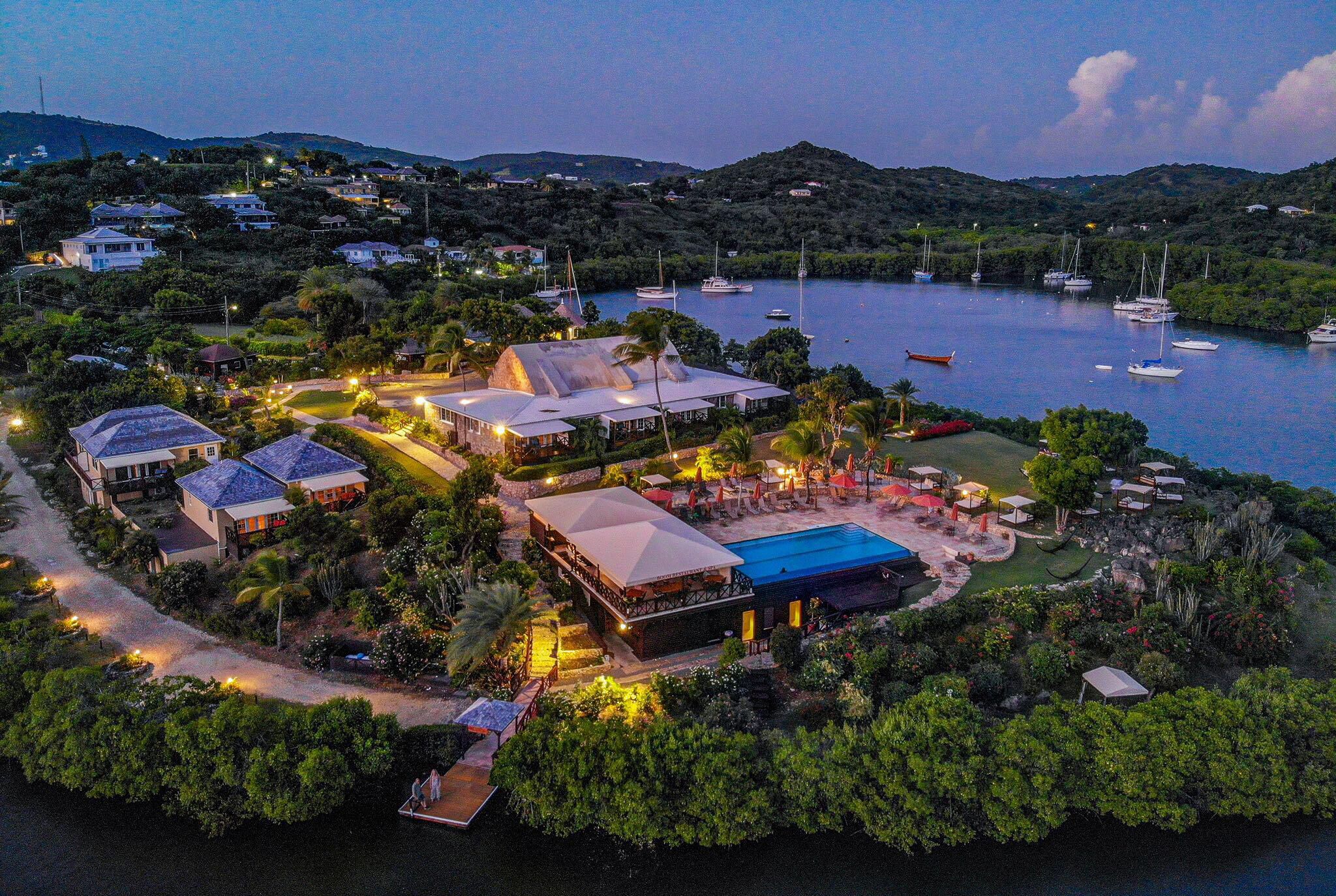An aerial view of a resort with multiple buildings, a swimming pool, and boats on a lake.