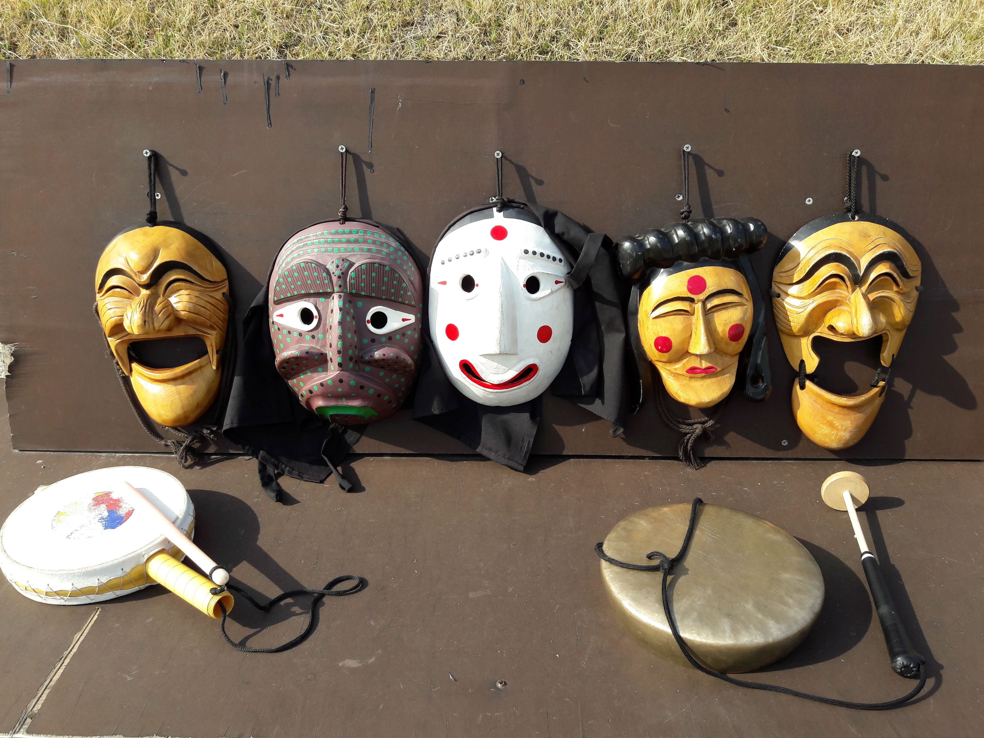 Five masks and two musical instruments on a brown surface.