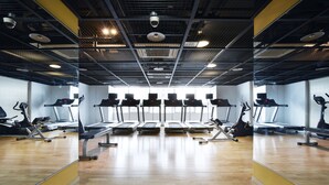 Une salle de sport équipée de tapis de course, de vélos d’appartement et d’appareils elliptiques.