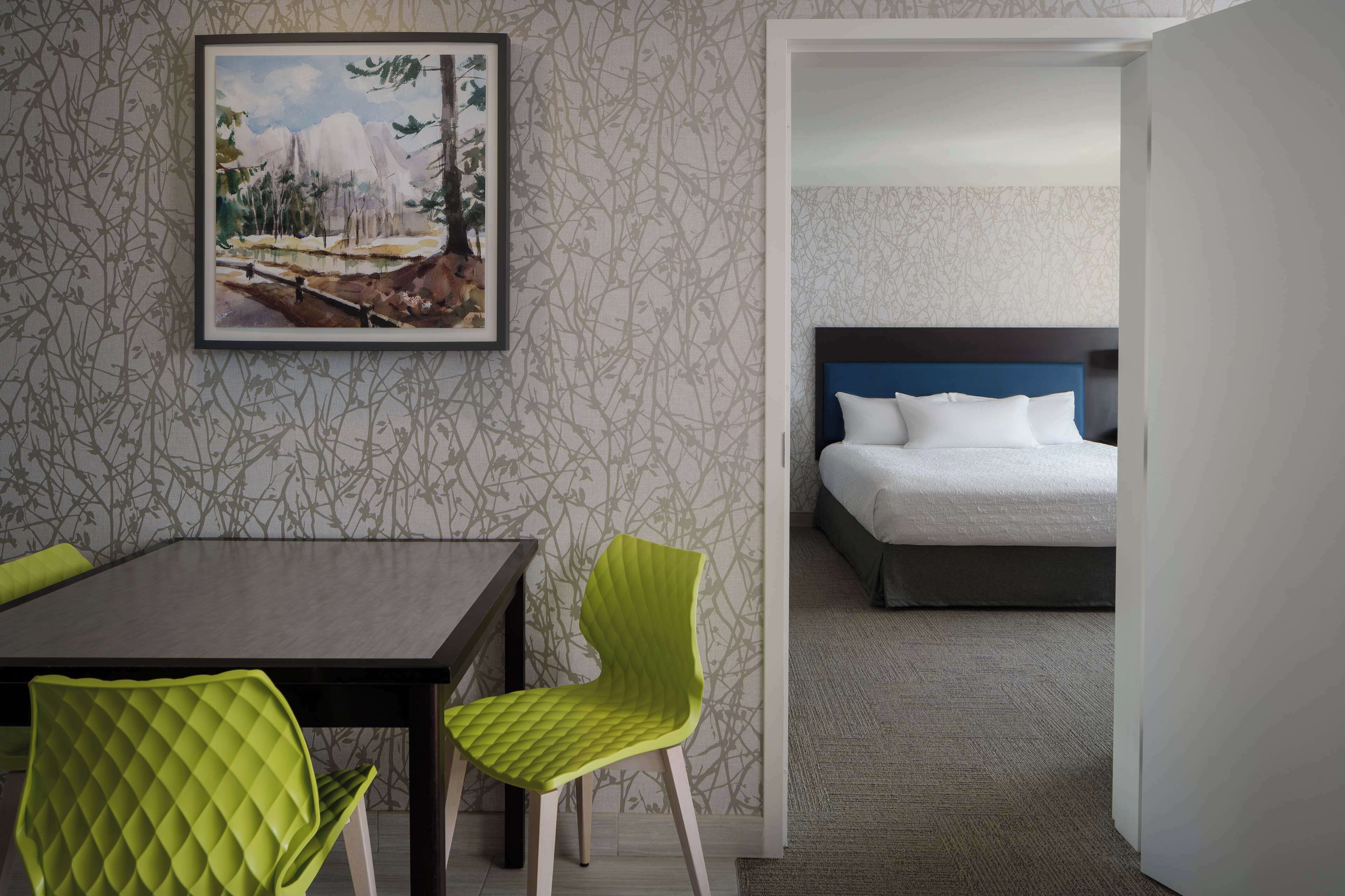 A hotel room with a bed, a desk, and two chairs.