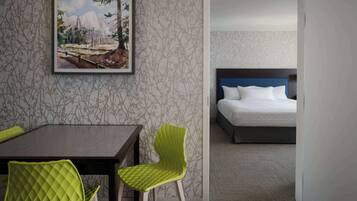 A hotel room with a bed, a desk, and two chairs.