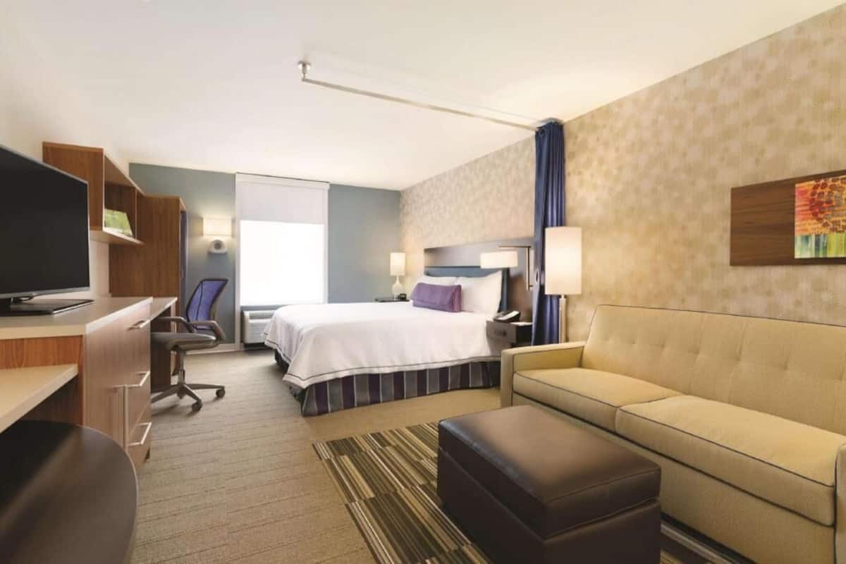 Une chambre d’hôtel comprenant un lit, un bureau, une chaise, un canapé et un téléviseur.