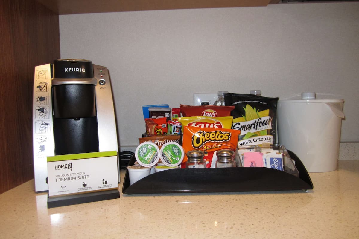 Une machine à café Keurig et un plateau contenant des collations et des condiments, pos és sur un comptoir de cuisine.