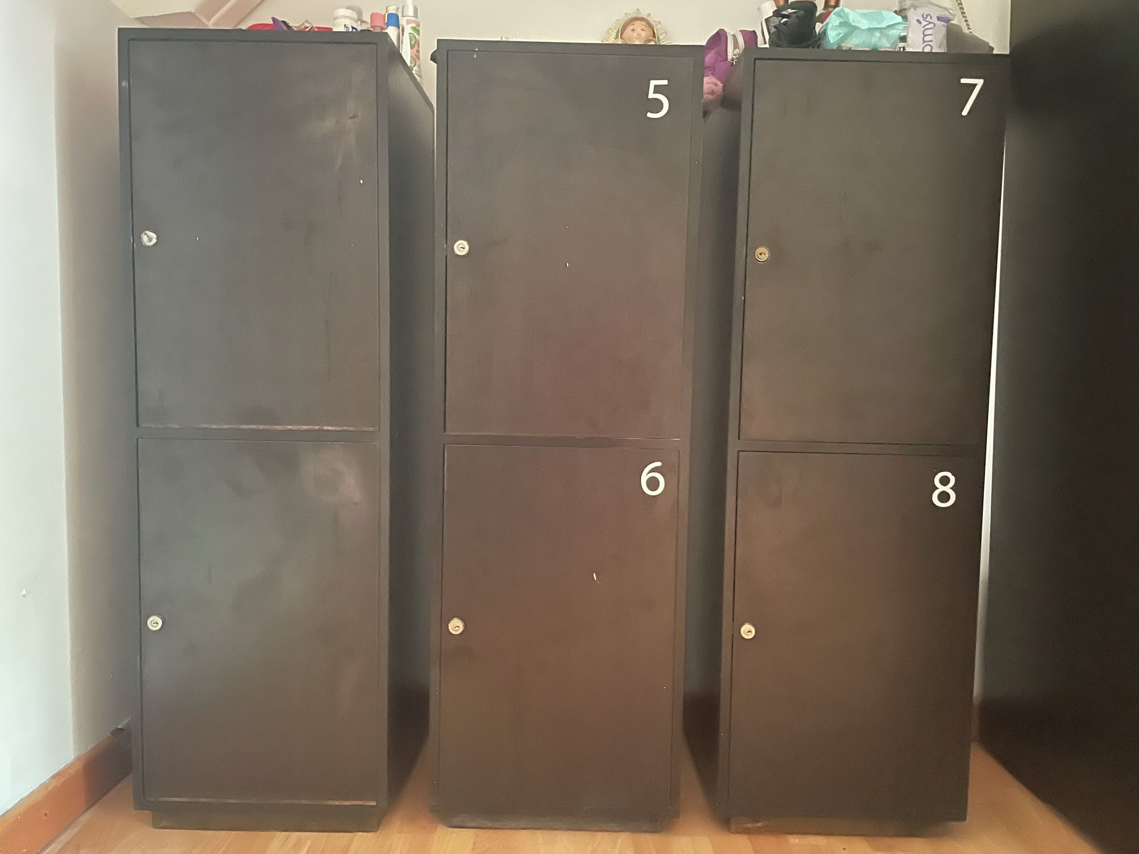 Three dark-colored metal lockers with numbers 5, 6, and 7 on the front.