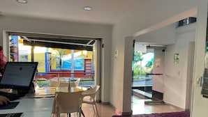 Een hotel lobby met een glazen deur naar buiten, een receptiebalie en een zithoek met een paars tapijt.