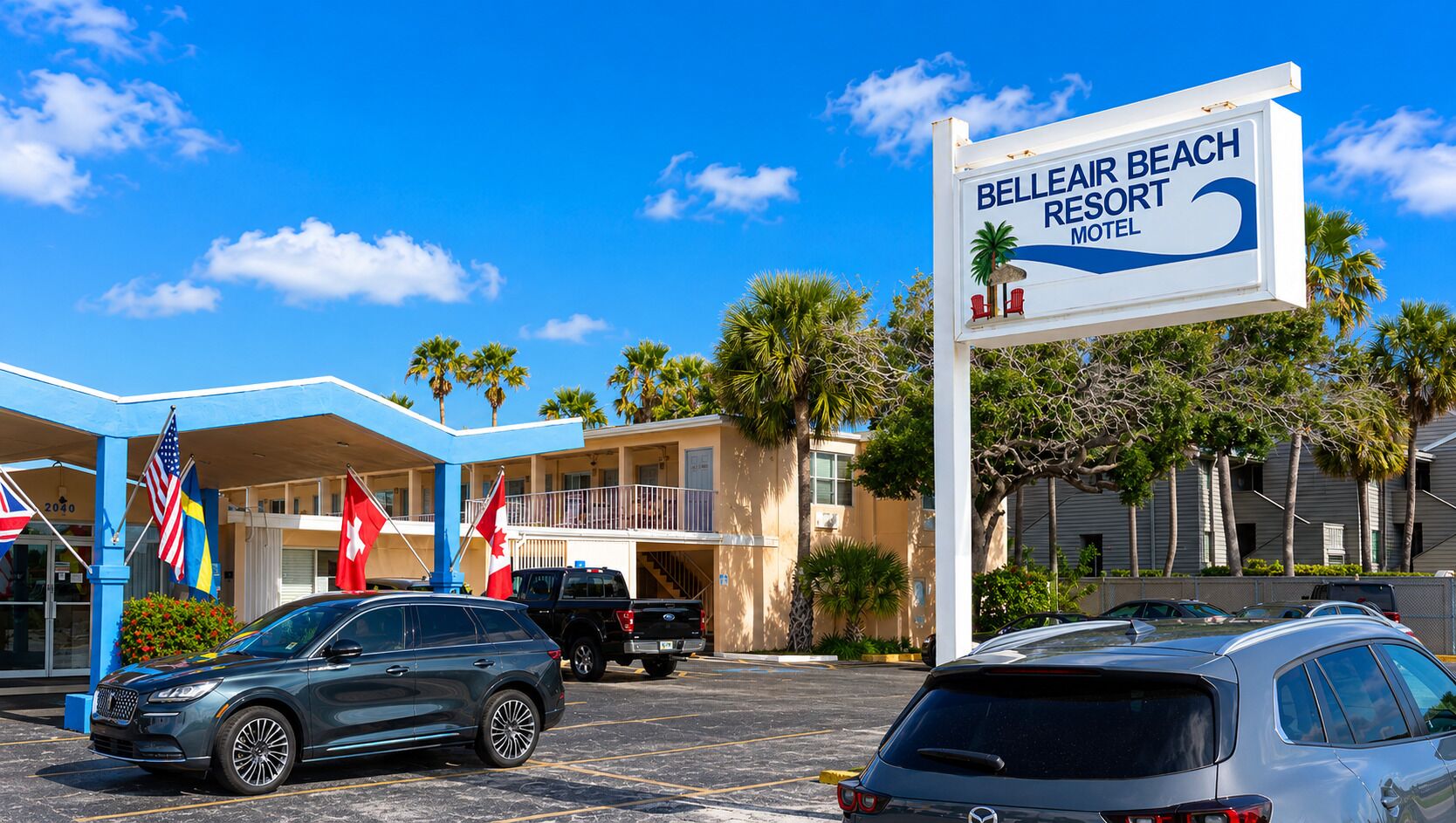 Resort Belleair Beach, con letrero, área de estacionamiento y banderas.