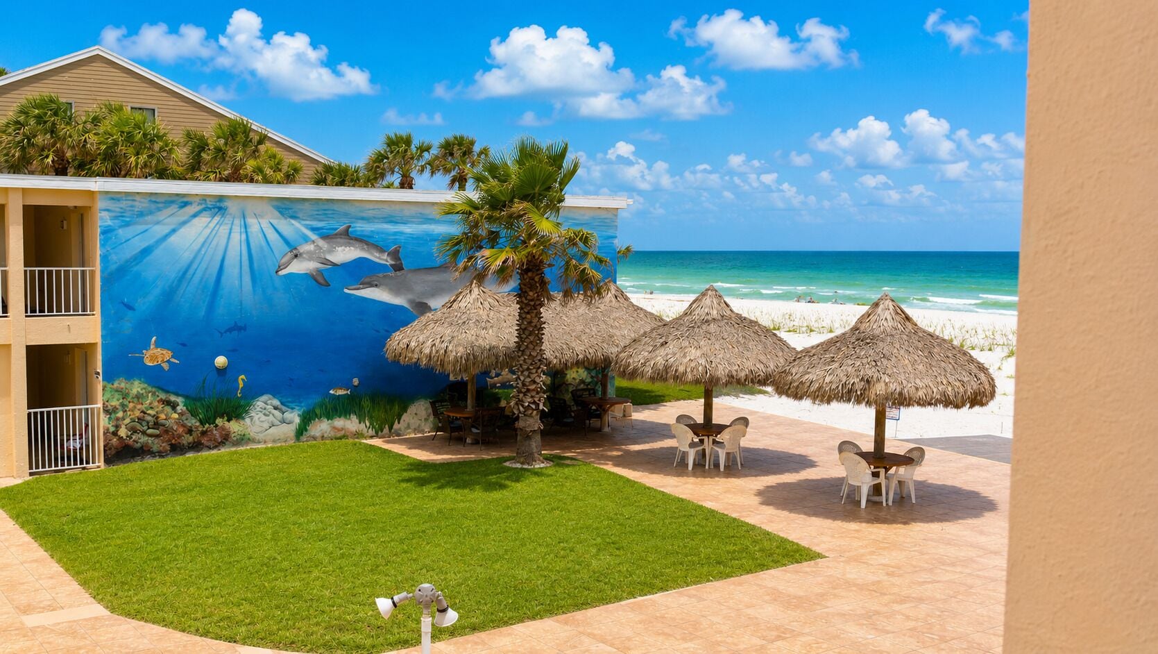A pool area with a mural of dolphins, palm trees, and a beach view.