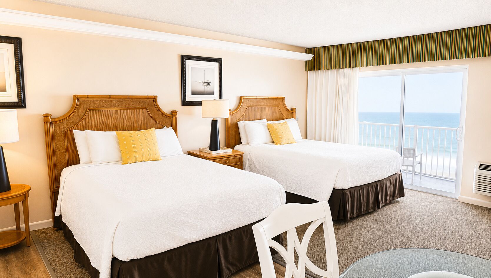 Habitación de hotel con dos camas, un balcón con vistas y un ventanal grande.