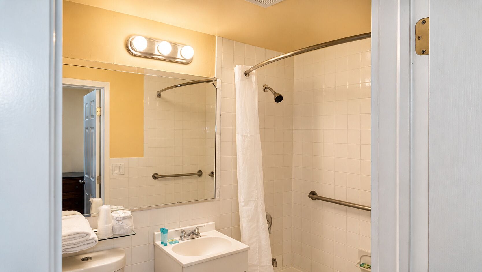 A bathroom with a shower, a sink, and a mirror.