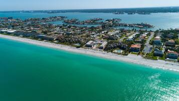 Vista aérea de una zona residencial costera con casas, una playa y un puerto deportivo.