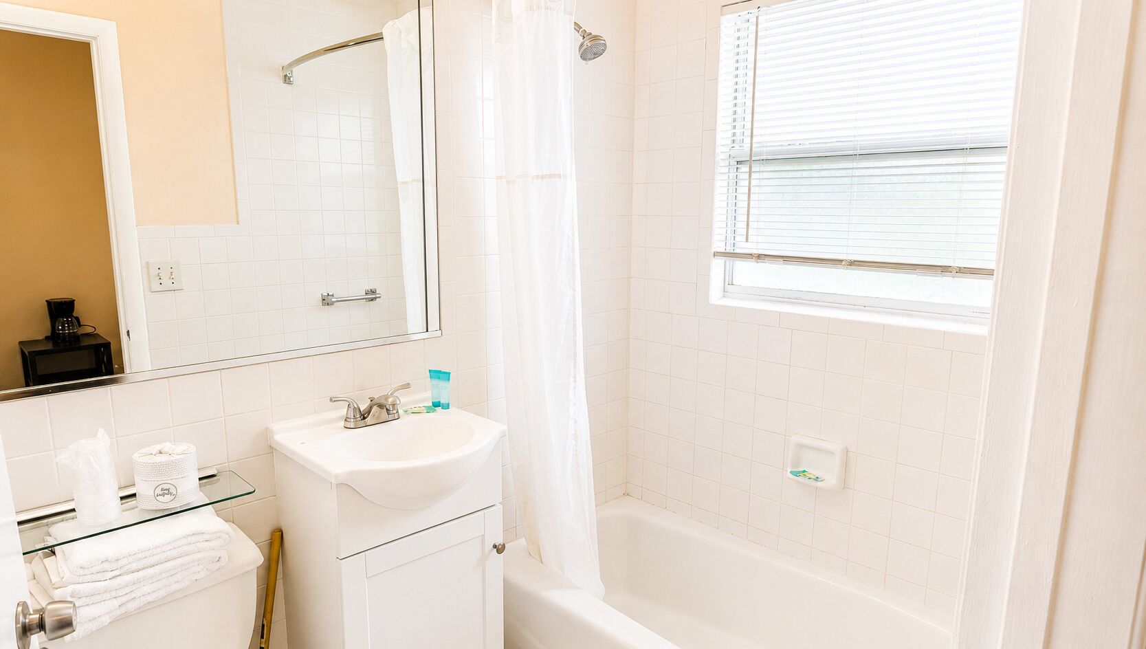 A bathroom with a white sink, mirror, and shower curtain.