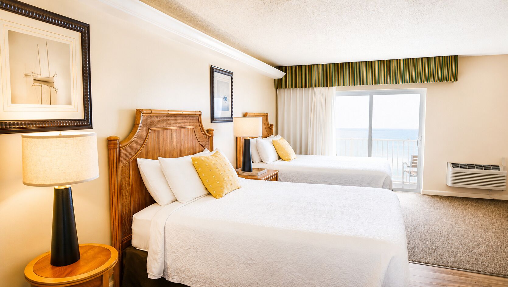 A hotel room with two beds, a large window with curtains, a framed picture on the wall, and a standing lamp.