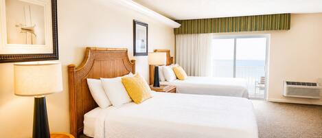 A hotel room with two beds, a large window with curtains, a framed picture on the wall, and a standing lamp.
