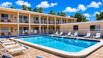 Un hotel con piscina, varios balcones y sillones de descanso.