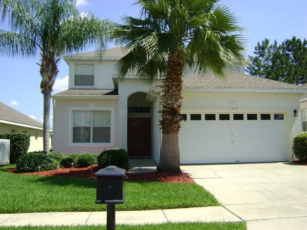 A single-story house with a garage, a palm tree, and a well-maintained lawn. - Highlands Reserve Villas (Davenport)