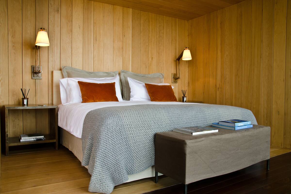 A neatly arranged bedroom with a bed, bedside tables, and a reading bench.