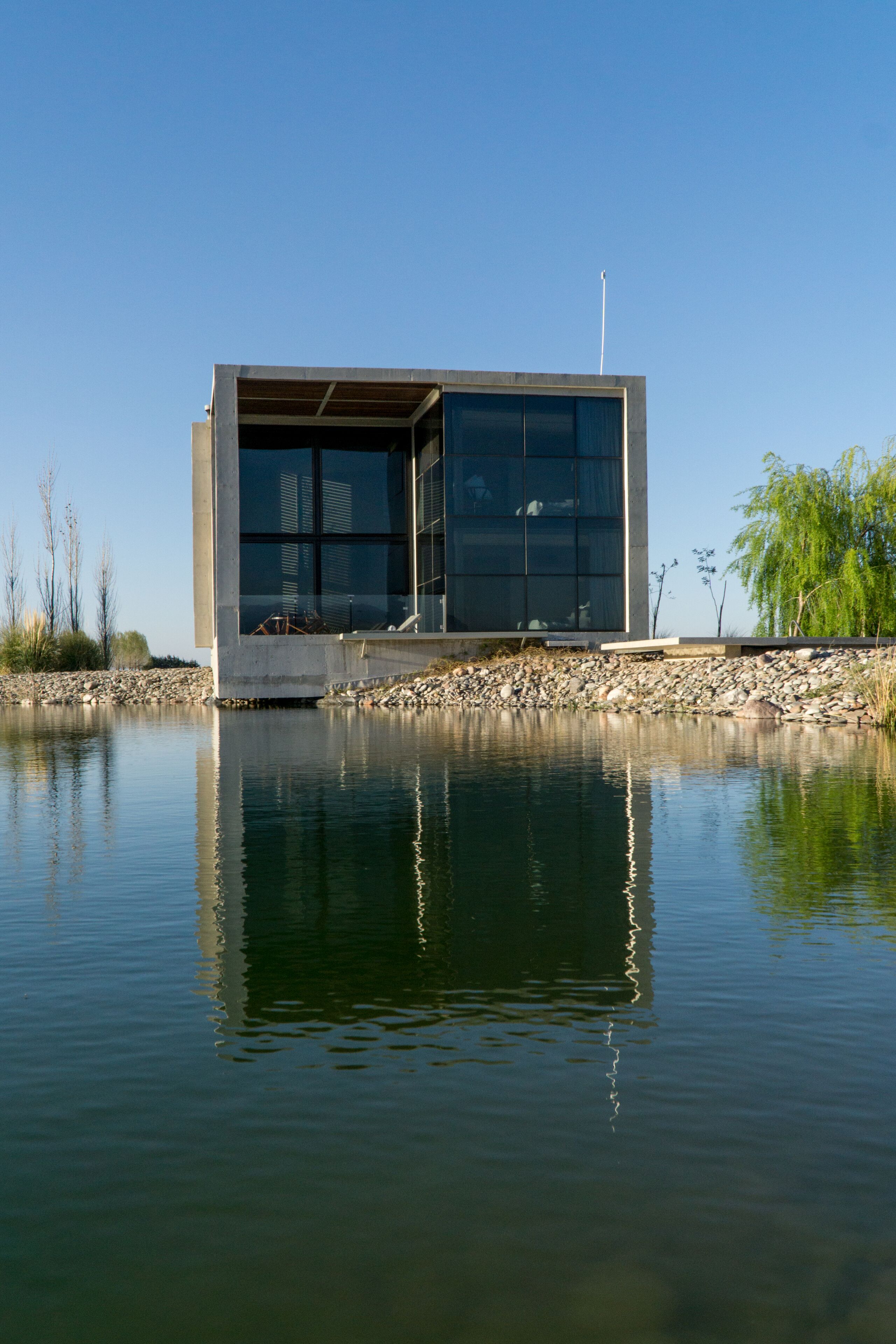 Un bâtiment moderne doté de grandes fenêtres, situé au bord d’une étendue d’eau paisible.
