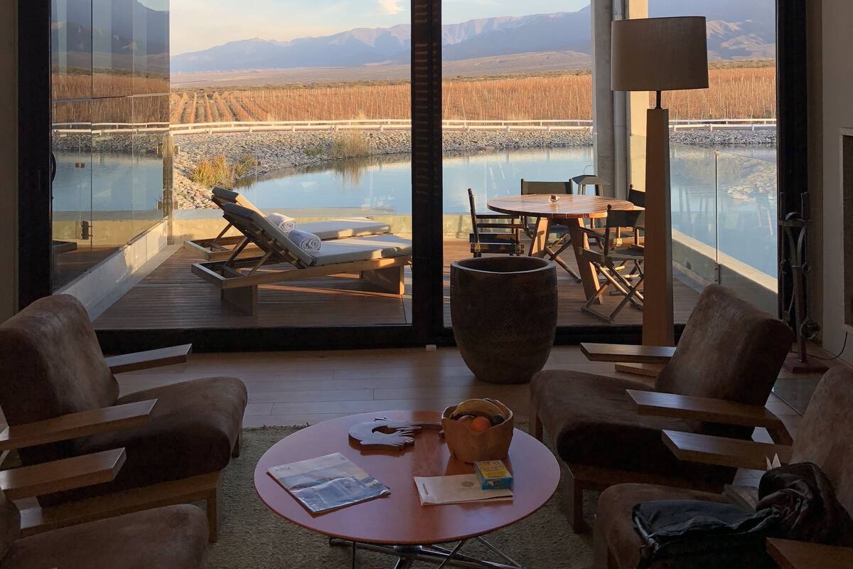 A modern interior with large windows overlooking a scenic outdoor view, including a body of water and mountains.
