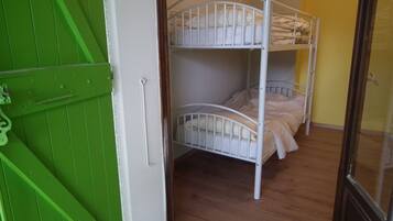A bunk bed room with a green door and wooden flooring.