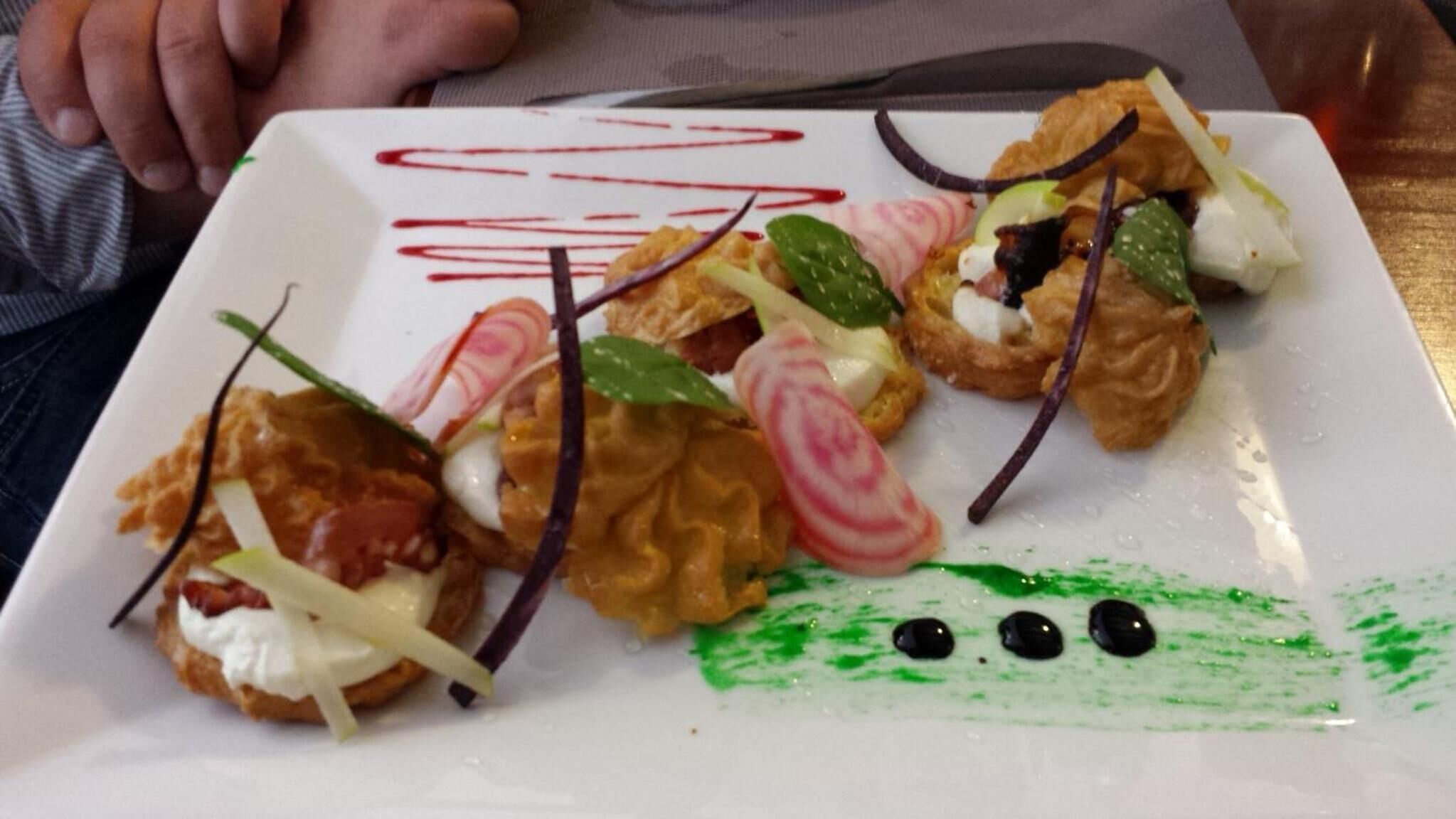 Une assiette d’amuse-gueules, agrémentée de diverses garnitures et d’un motif décoratif en forme de ligne rouge.