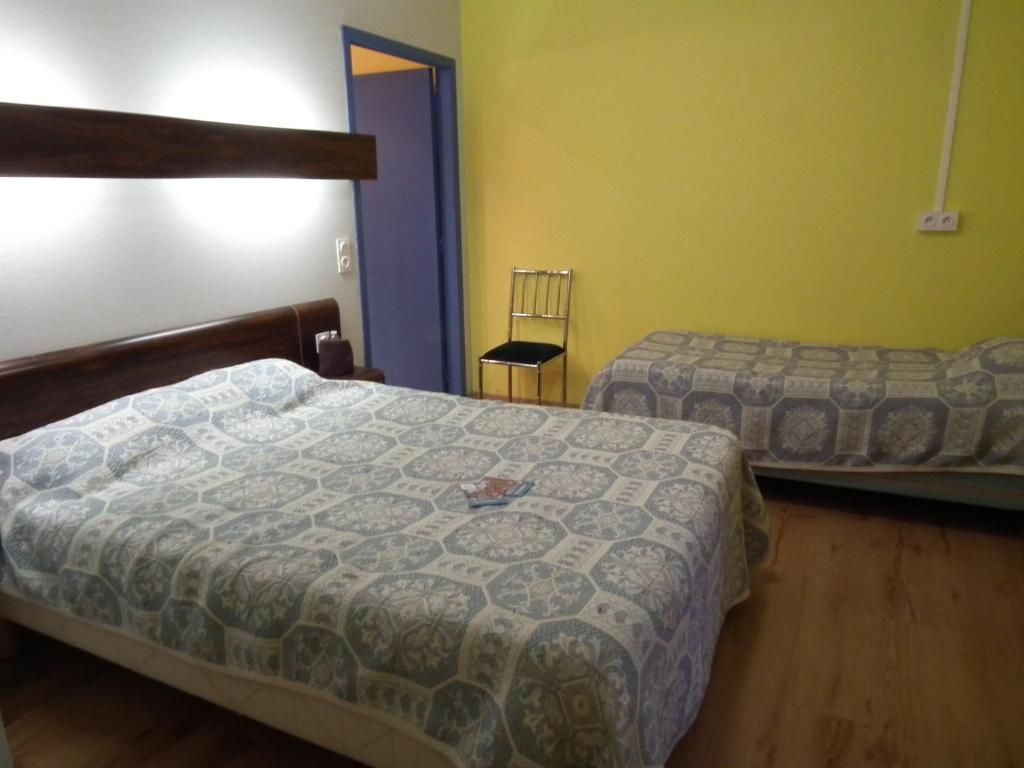 A bedroom with two beds, a chair, and a door.