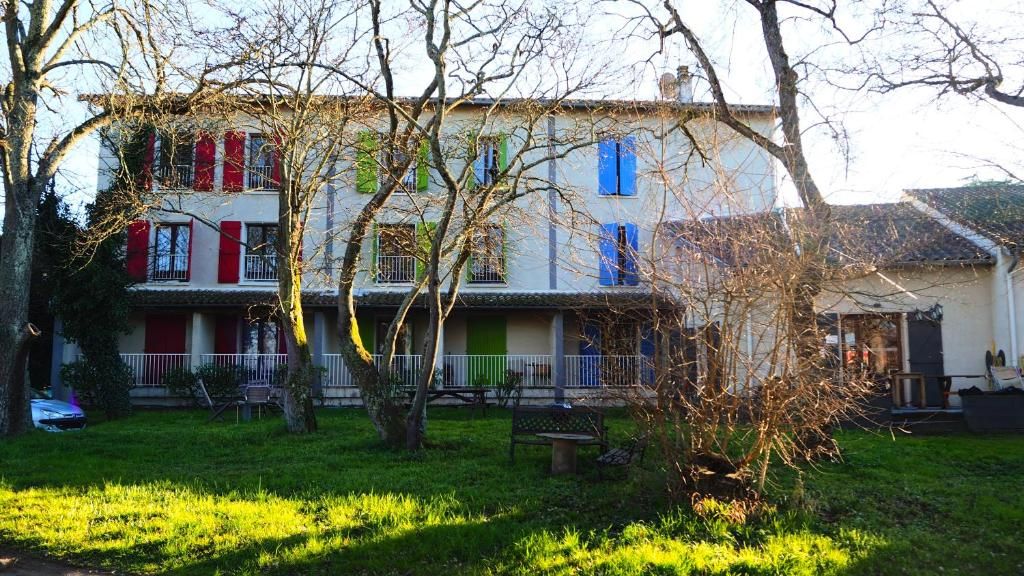 Ein zweistöckiges Gebäude mit Balkon und einem kleinen Garten davor.