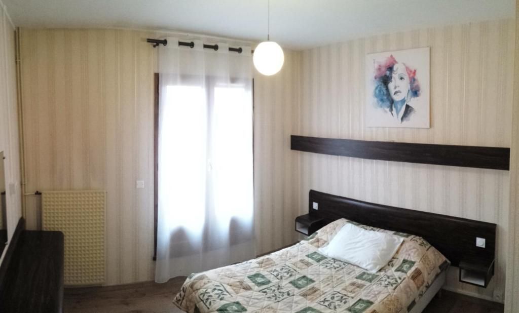 Une chambre à coucher avec un lit, des rideaux, un radiateur, une étagère fixée au mur et un tableau.