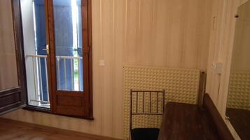 Una habitación con suelo de madera, un radiador, una silla de metal y un banco de madera.