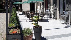 An outdoor patio area with tables and chairs, a pergola, and potted plants. - Friendly Auberge - Hostel (Colomiers)