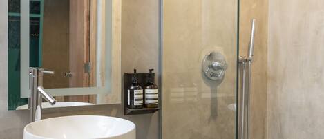 Un baño moderno con un lavamanos grande, una ducha con cerramiento de vidrio y un espejo con marco de madera.