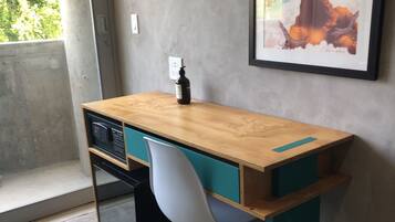 A small, compact workspace with a wooden desk, teal chair, and a black heater.