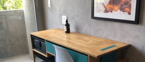 A small, compact workspace with a wooden desk, teal chair, and a black heater.
