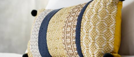 Una cama con un cojín decorativo y una lámpara colgante.