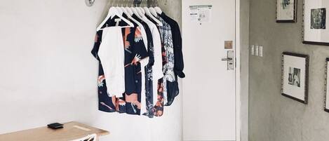 A hallway with a coat rack holding several garments, a desk with a chair, and a door with a notice on it.