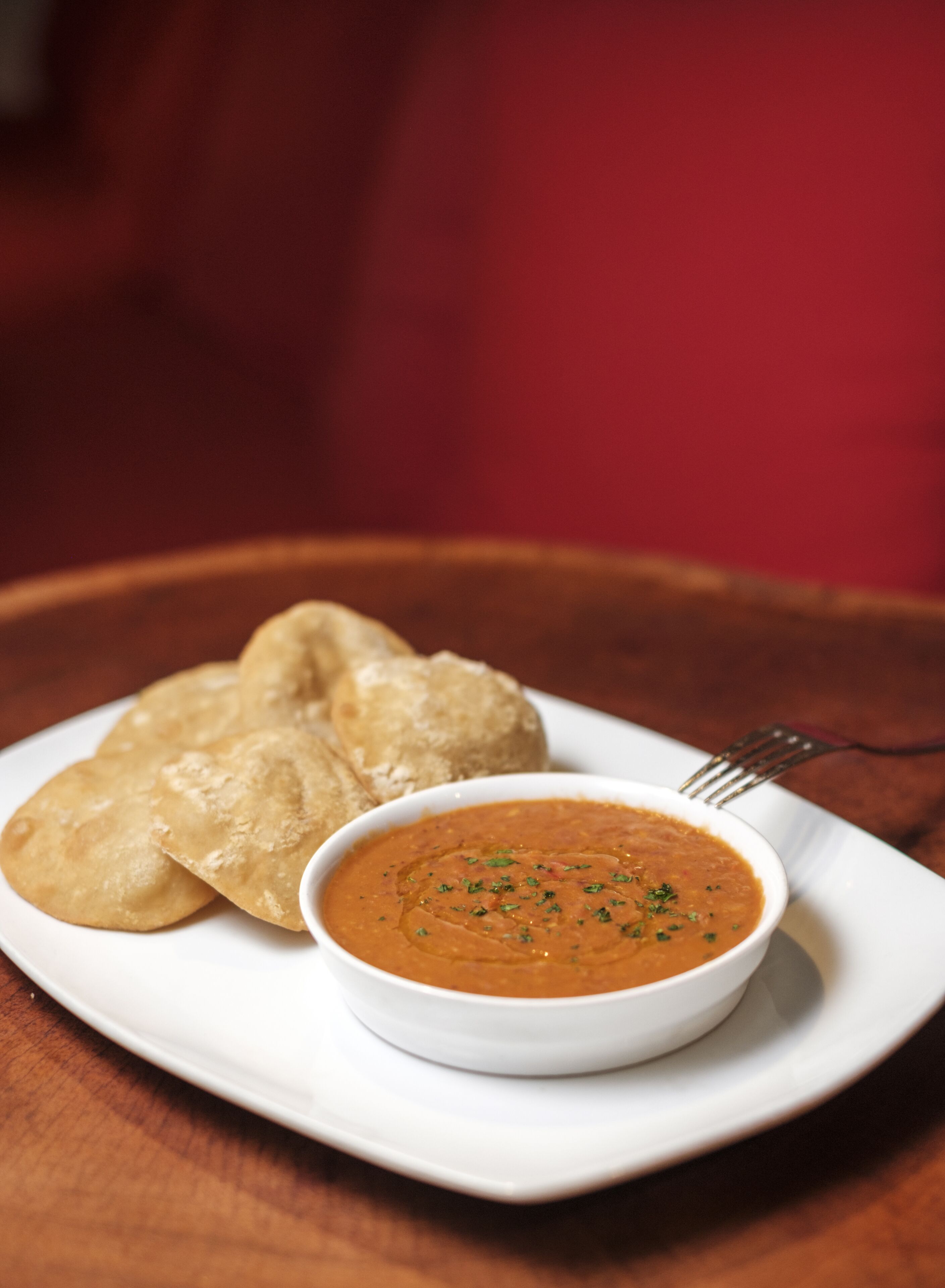 A plate with two pieces of flatbread and a bowl of soup.