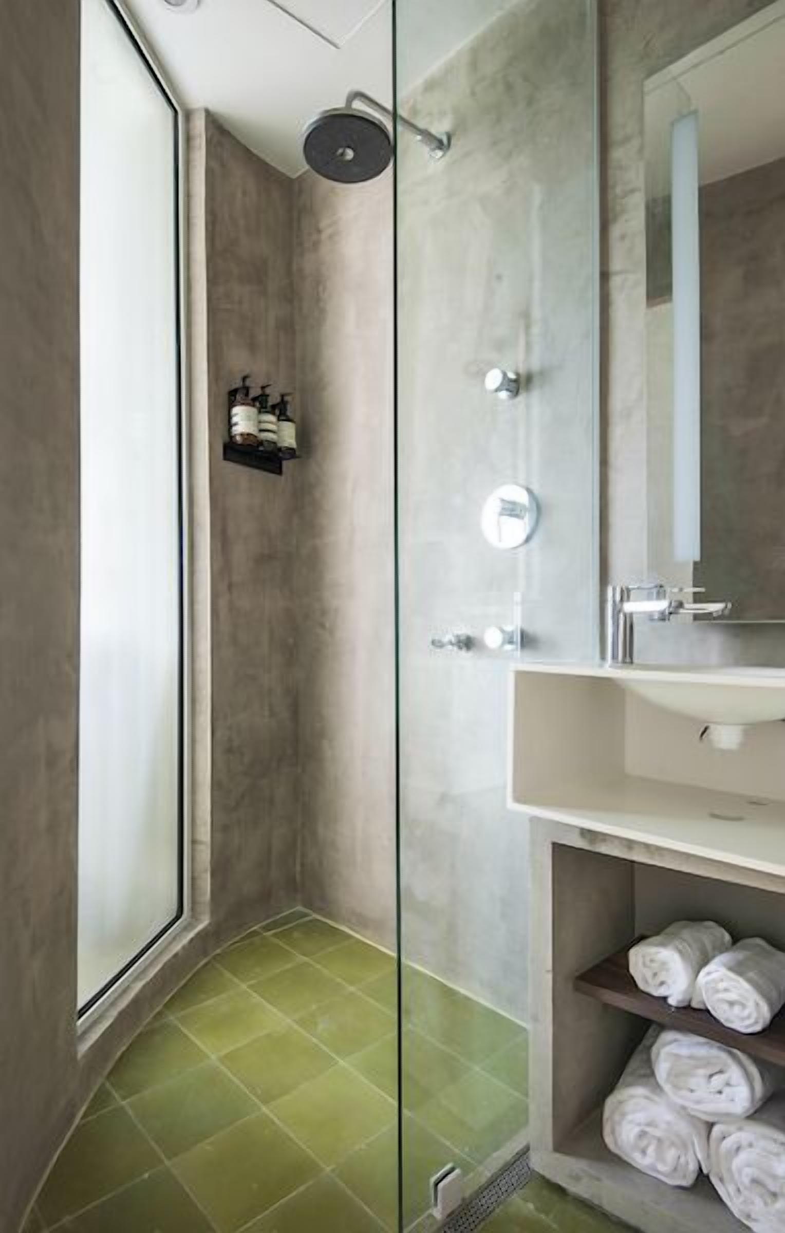 A modern bathroom with a glass shower enclosure, a white sink, and a mirror.