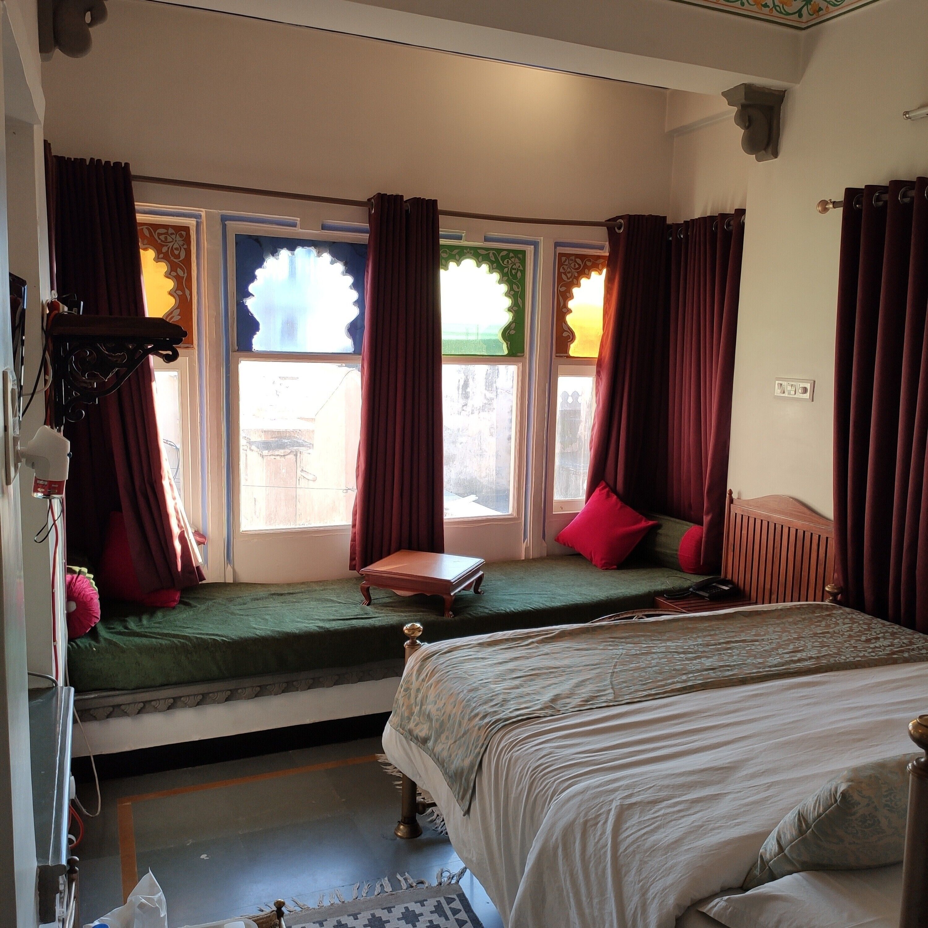 A bedroom with a bed, a small table, and a window with curtains.