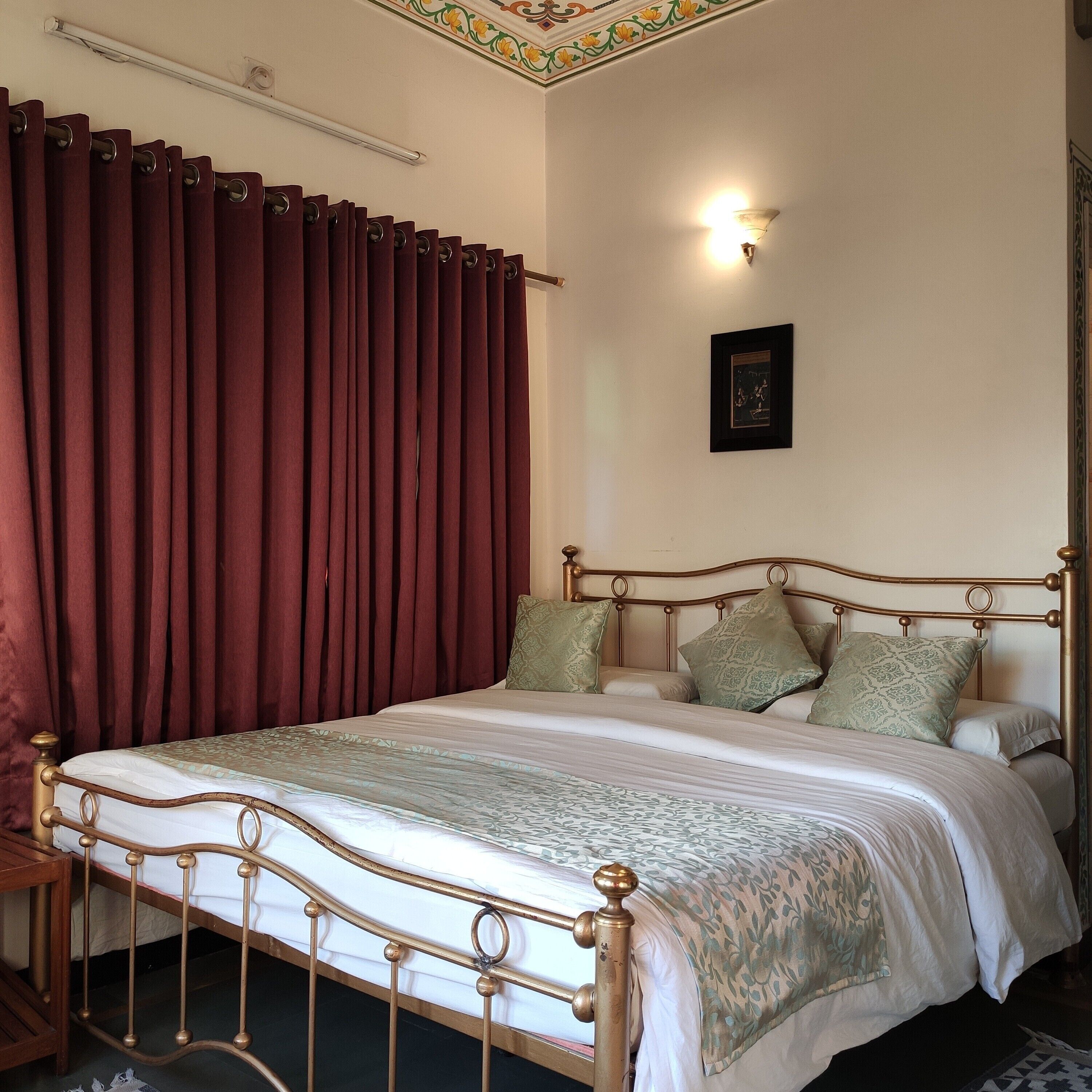 A neatly made bed with a patterned bedspread, a wooden headboard, and green pillows.